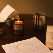 Candle, mug, and books on a table with warm lighting