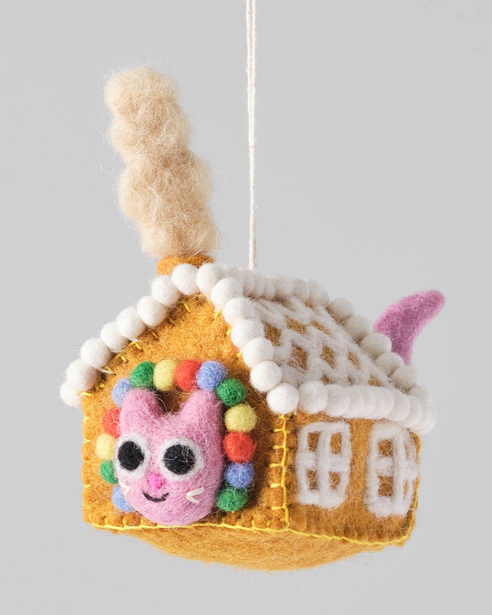 Felted animal house ornament with a pink face on a gray background.