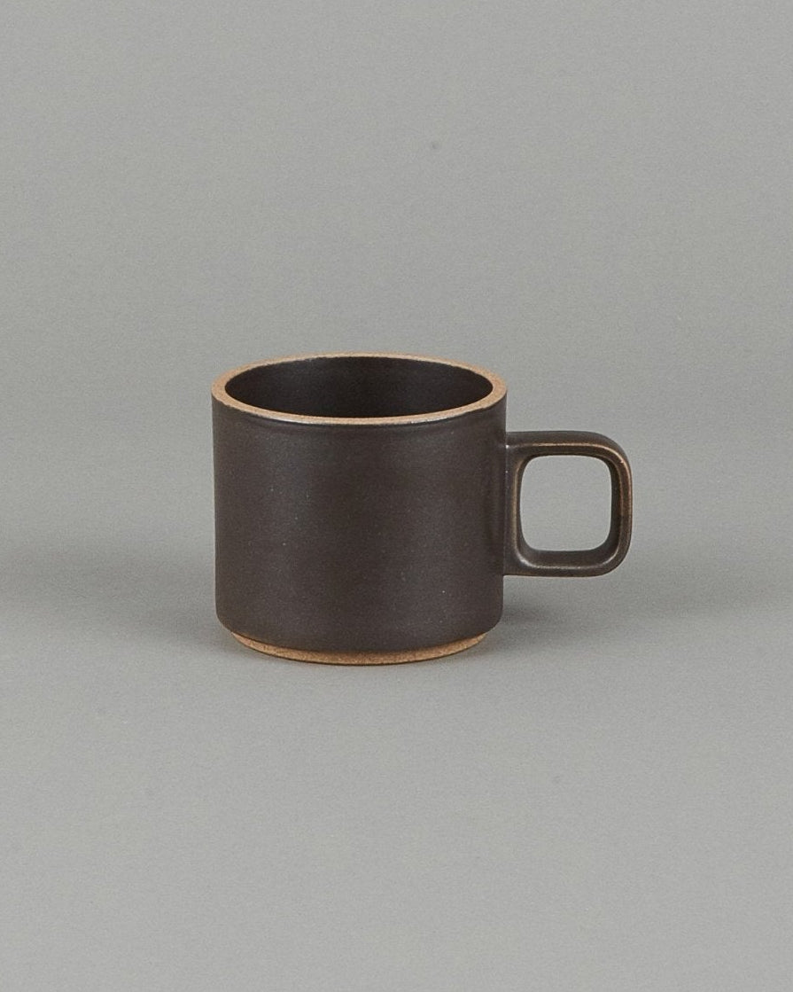 Small brown ceramic mug on a gray background