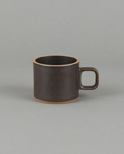 Small brown ceramic mug on a gray background